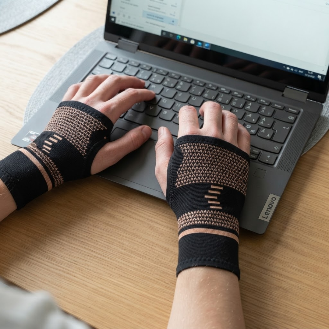 Person med håndledsstøtter med kobber skriver på bærbar computer